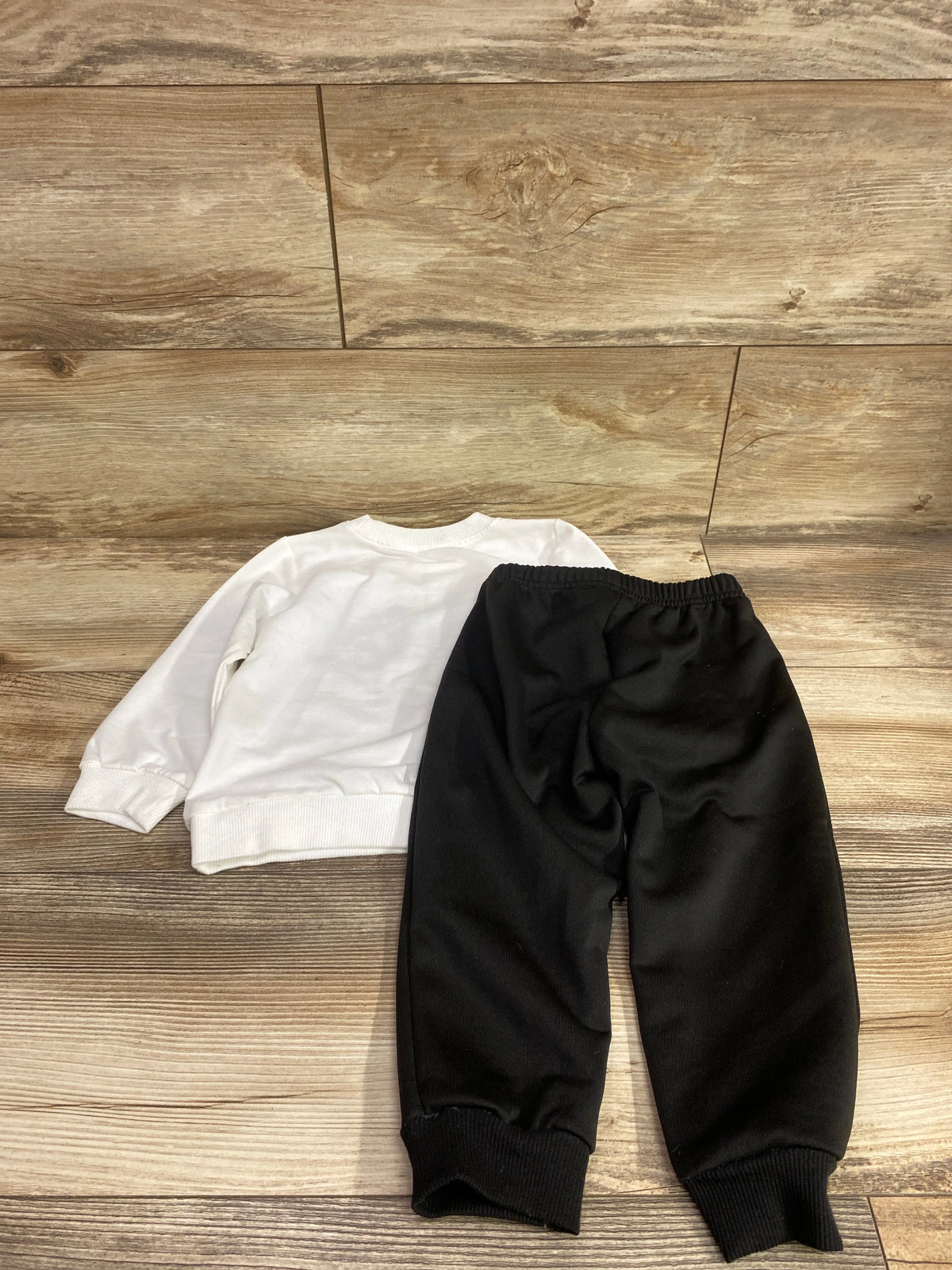 Overhead view of Shein Coolqubz All New Things set showing white sweatshirt and black pants, size 18 to 24 months, on wood backdrop