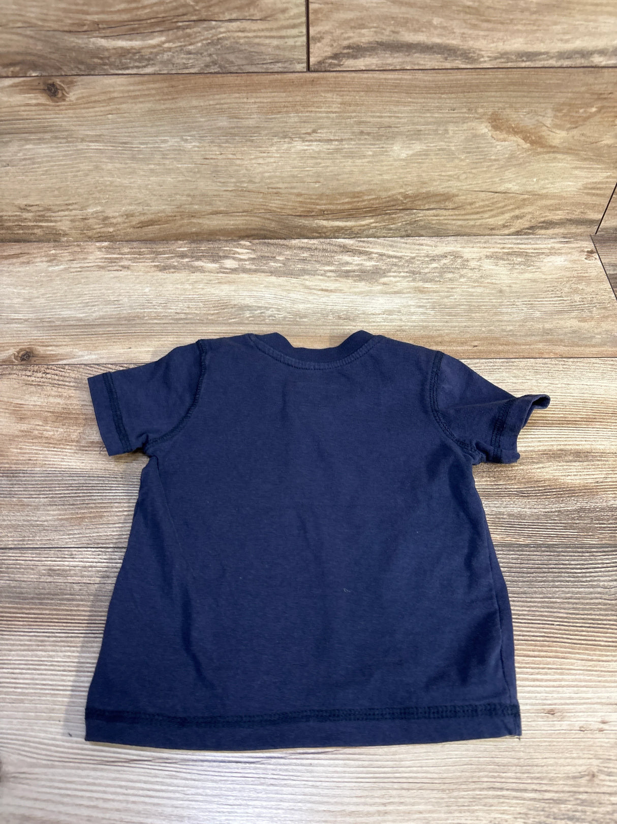 Back view of Joe’s V-neck toddler shirt size 2T showing navy short sleeves and straight hem laid flat on wood background