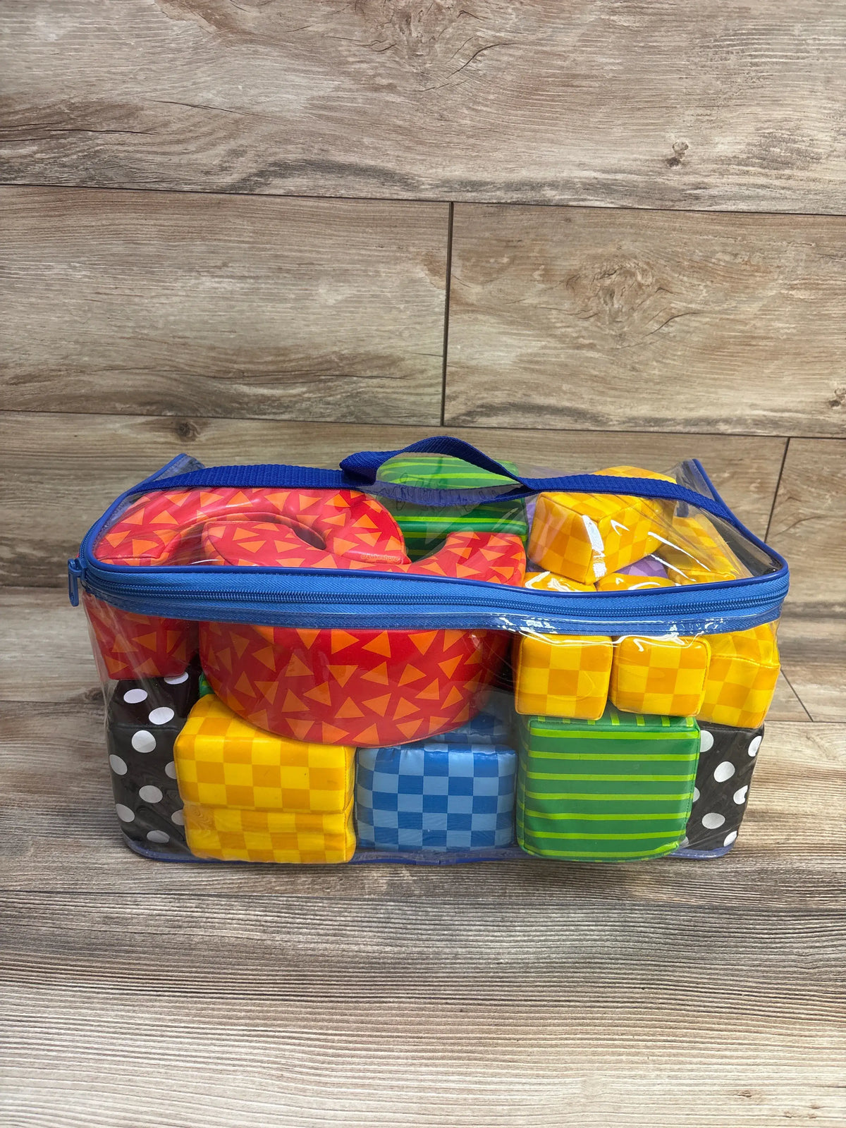 Front view of 22-piece Lakeshore Soft & Safe building blocks showing colorful patterned soft foam blocks inside a clear zip carrying case on a wood floor