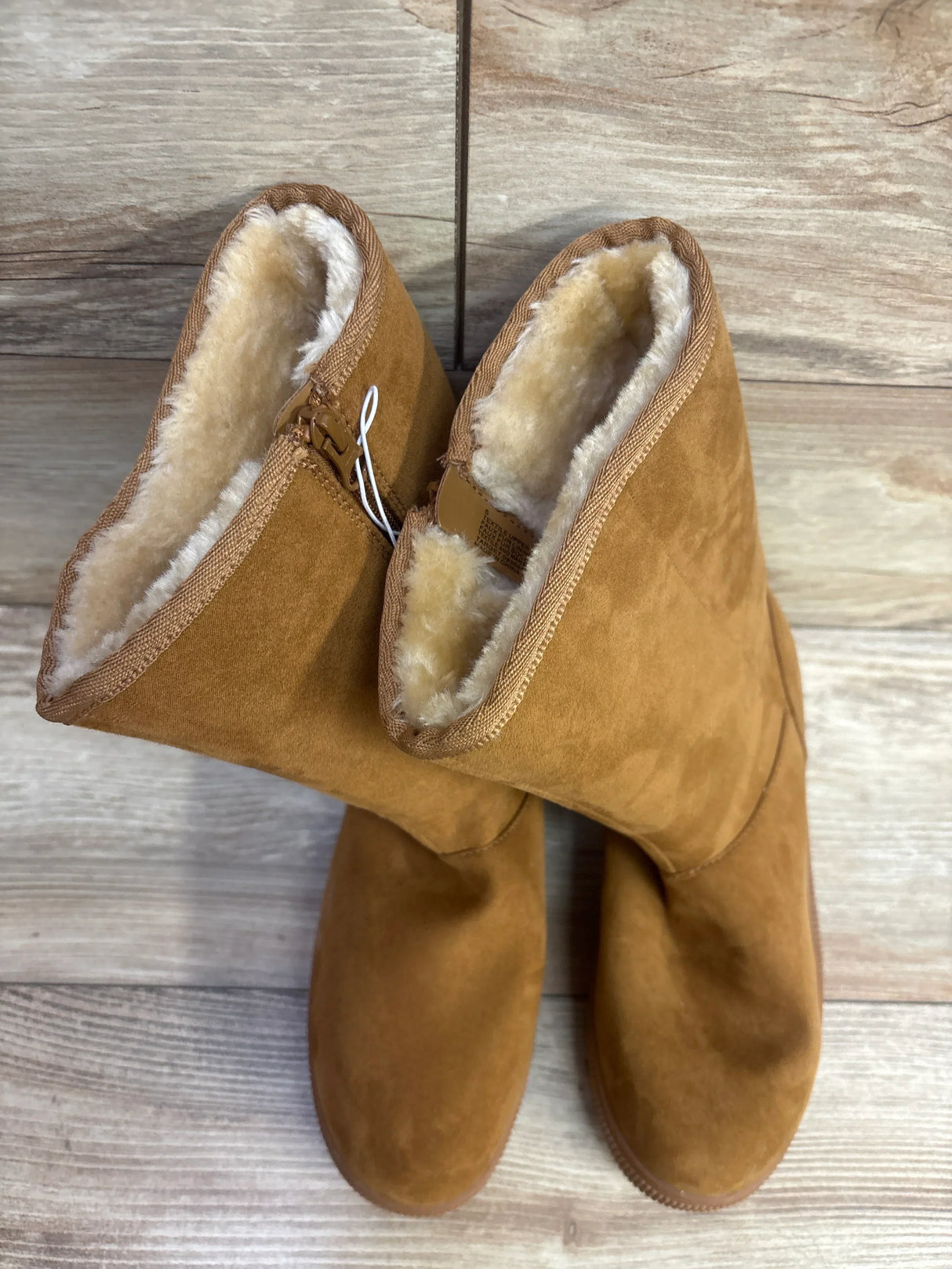 Brown suede kids boots with plush fleece lining on wooden floor