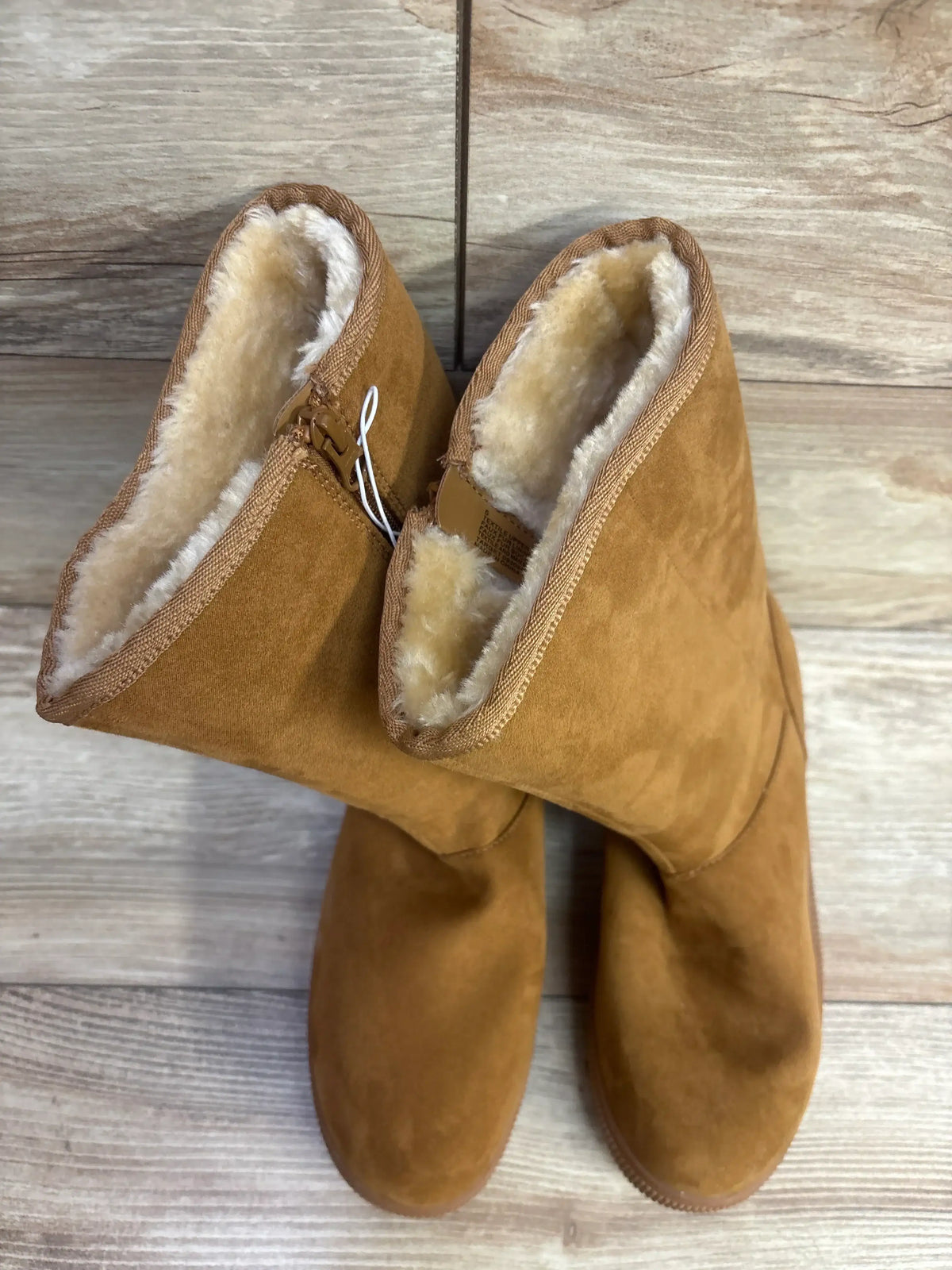 Brown suede kids boots with plush fleece lining on wooden floor