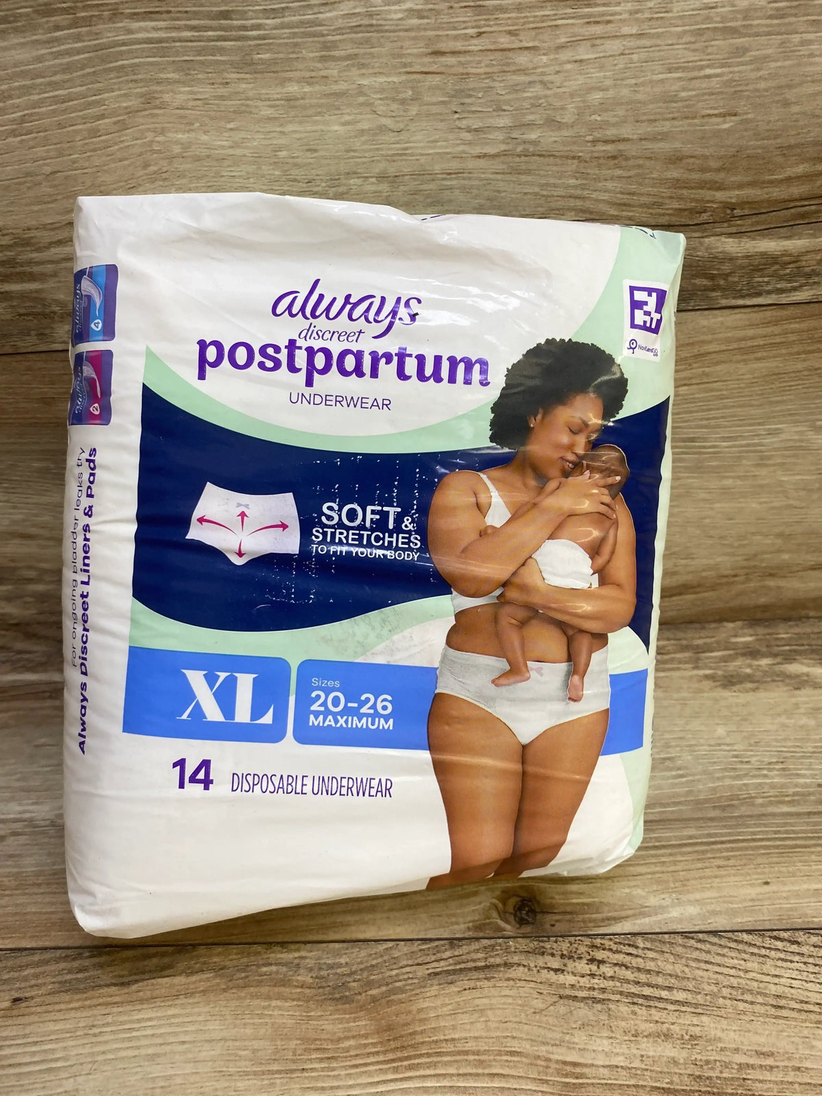 Front of Always Discreet Postpartum underwear pack showing XL (sizes 20-26), “Soft and Stretches” callout, 14-count disposable underwear on wood background
