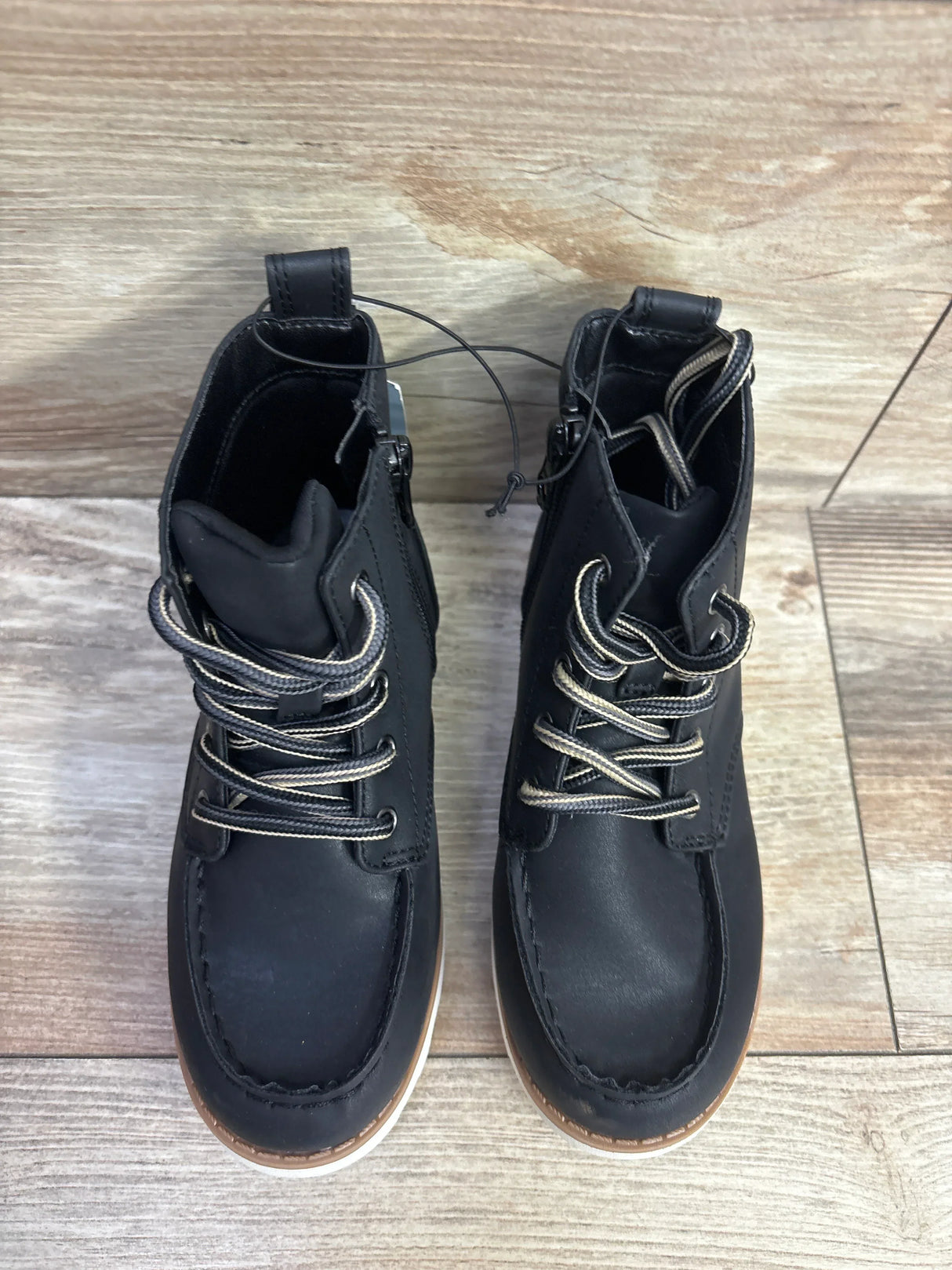 Top-down view of Cat & Jack Greyson kids' black lace-up boots size 11C showing brown trim and white midsoles on wood floor
