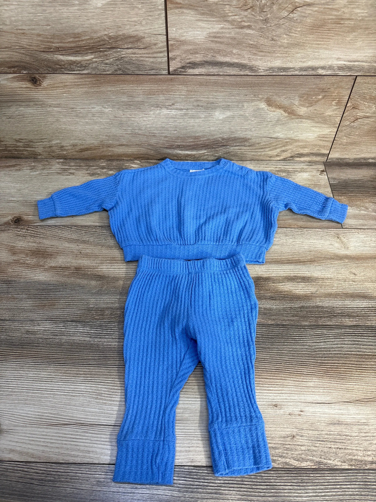 Overhead view of Cat & Jack two-piece blue textured shirt and pants set, size 3-6 months, on wood floor