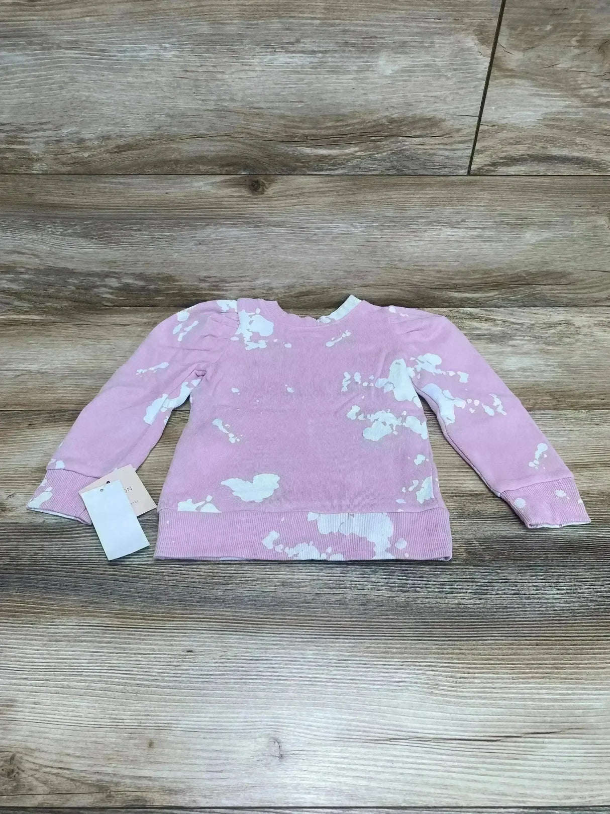 Front view of pink toddler sweatshirt 2T showcasing mini puff sleeves and white bleach-splotch pattern on wood background