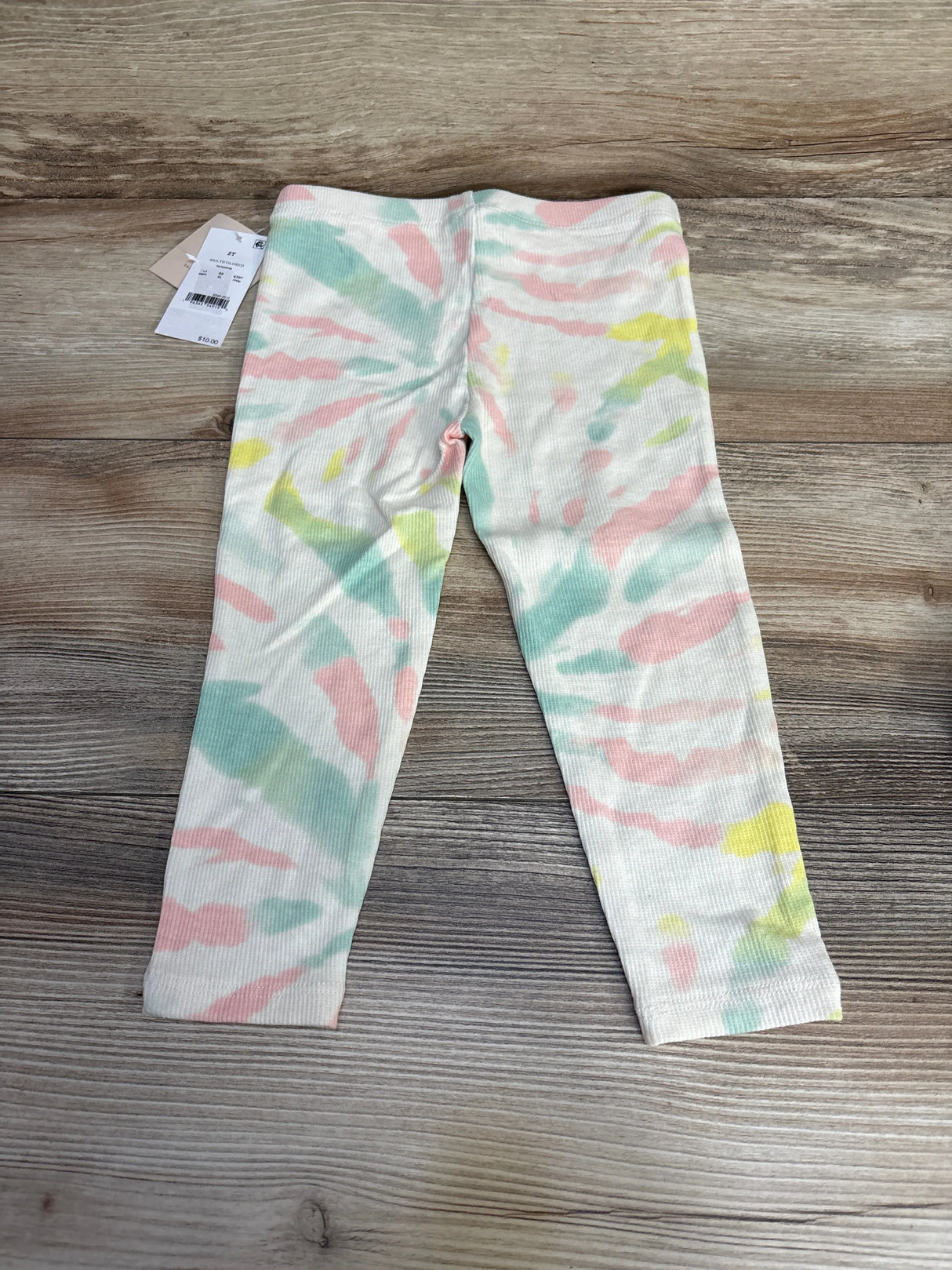 Front flat lay of Grayson tie-dye leggings, cream with pastel pink, mint and yellow print, ribbed texture on wood, size 2T