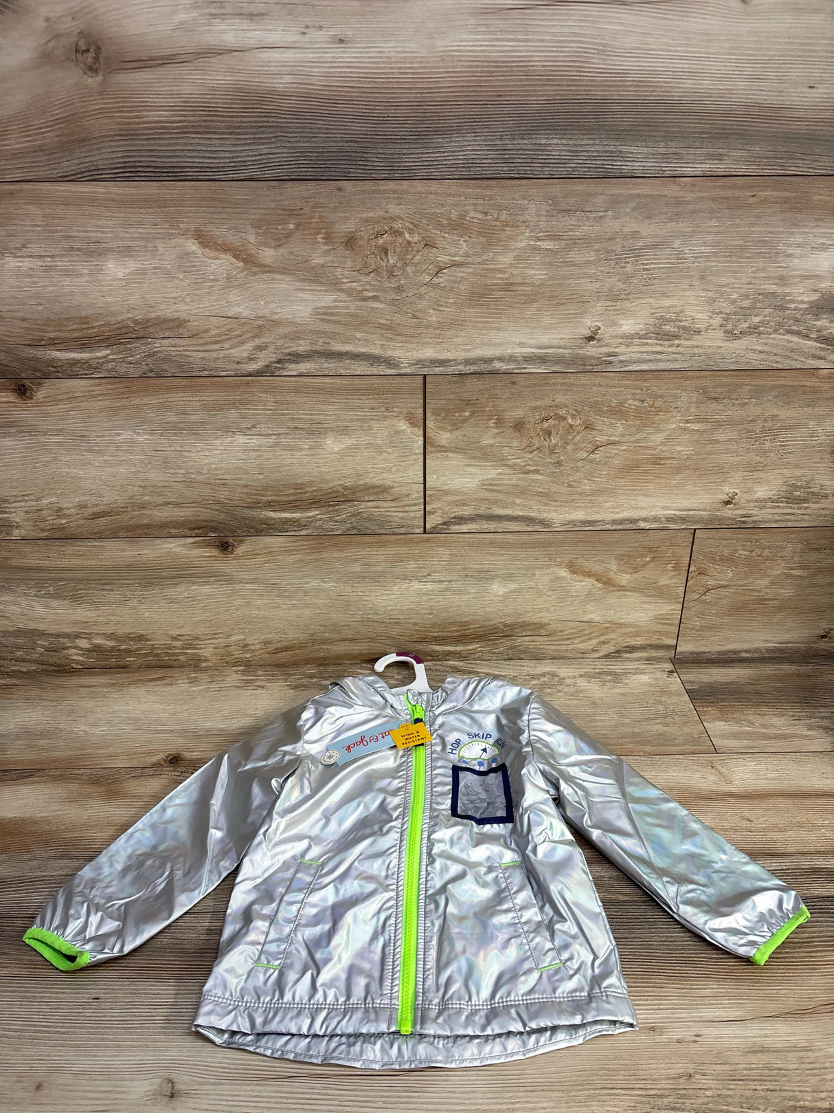 Front view of holographic silver rain jacket (3T) with lime green zipper and cuffs and Hop Skip patch on chest