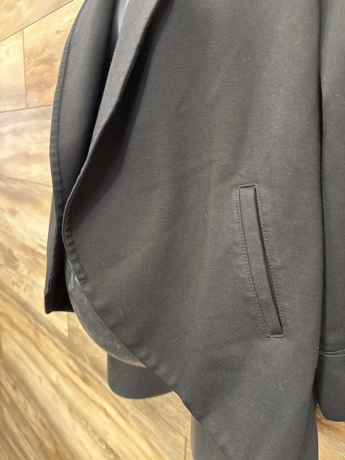 Black blazer jacket with pocket detail on wooden background
