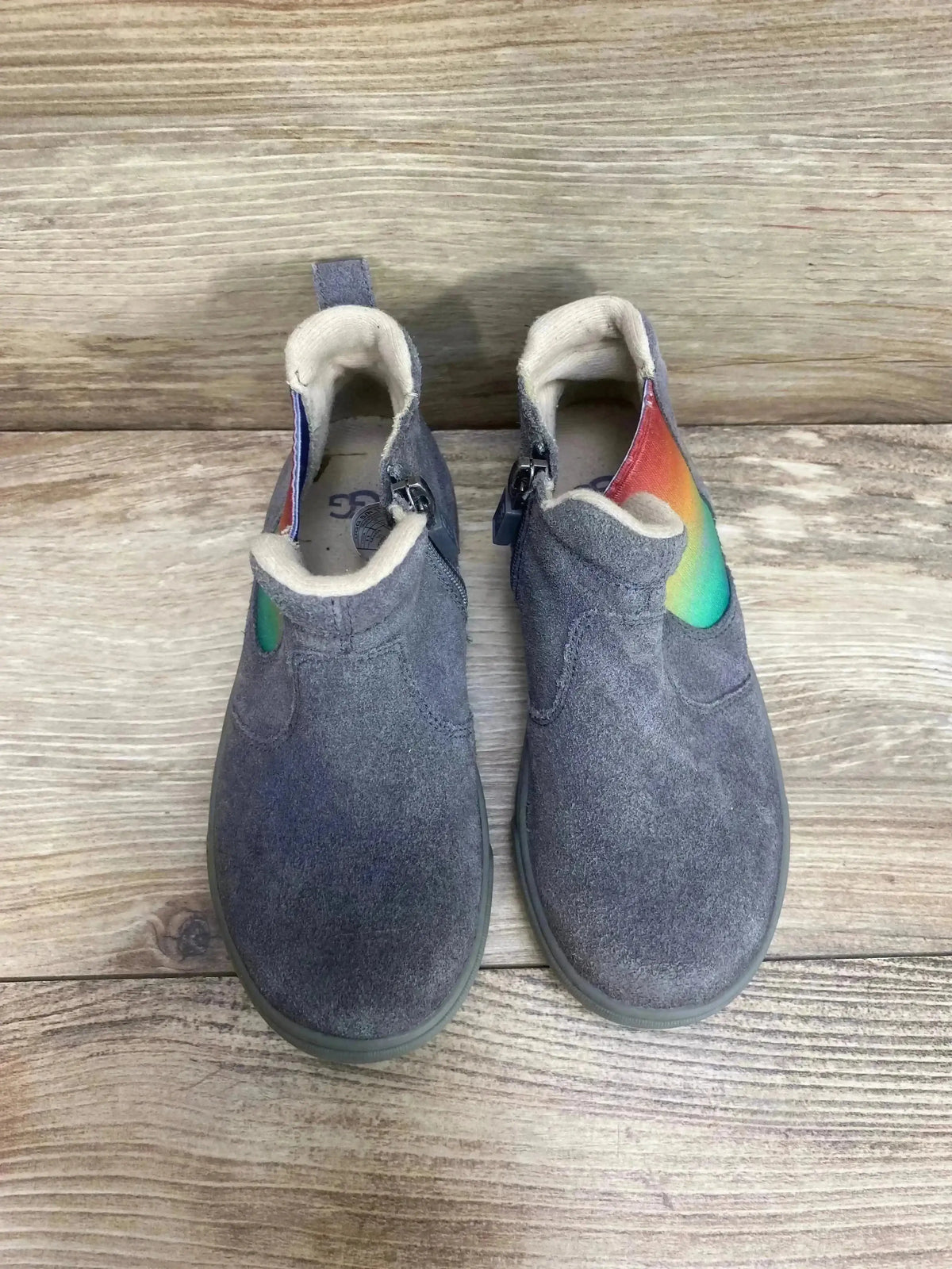 Top-down view of UGG Hamden II toddler suede sneakers in grey showing rainbow heel tab and side zipper on wood floor background