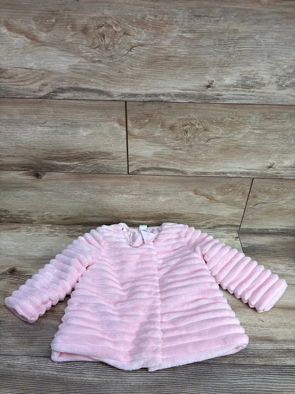 Little Me faux fur pink baby coat for size 18m on a wooden background