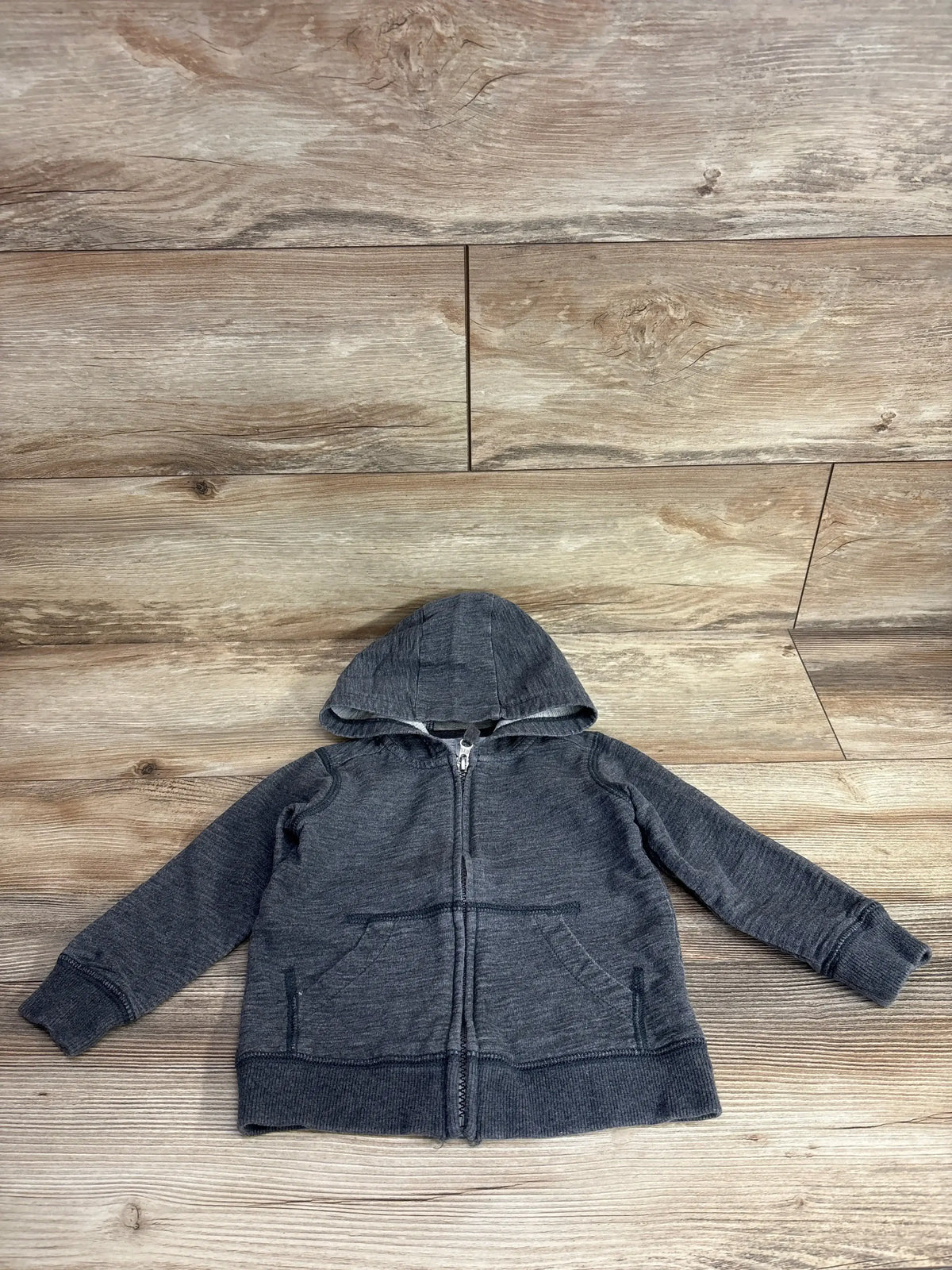 Dark gray zip-up toddler hoodie with pockets, displayed on wood background