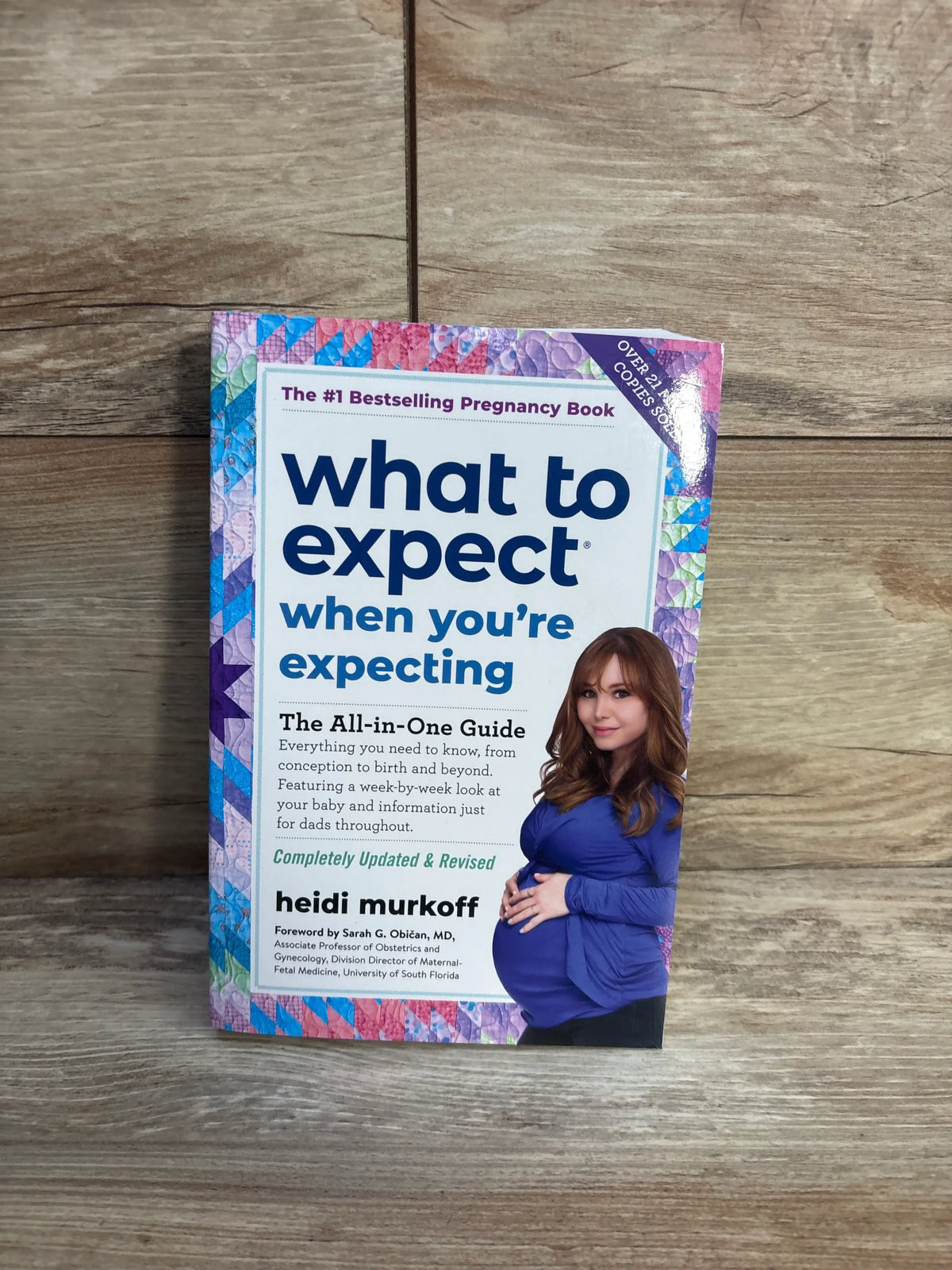 Front view of What to Expect When You’re Expecting 5th Edition paperback showcasing a pregnancy guide cover on wood floor