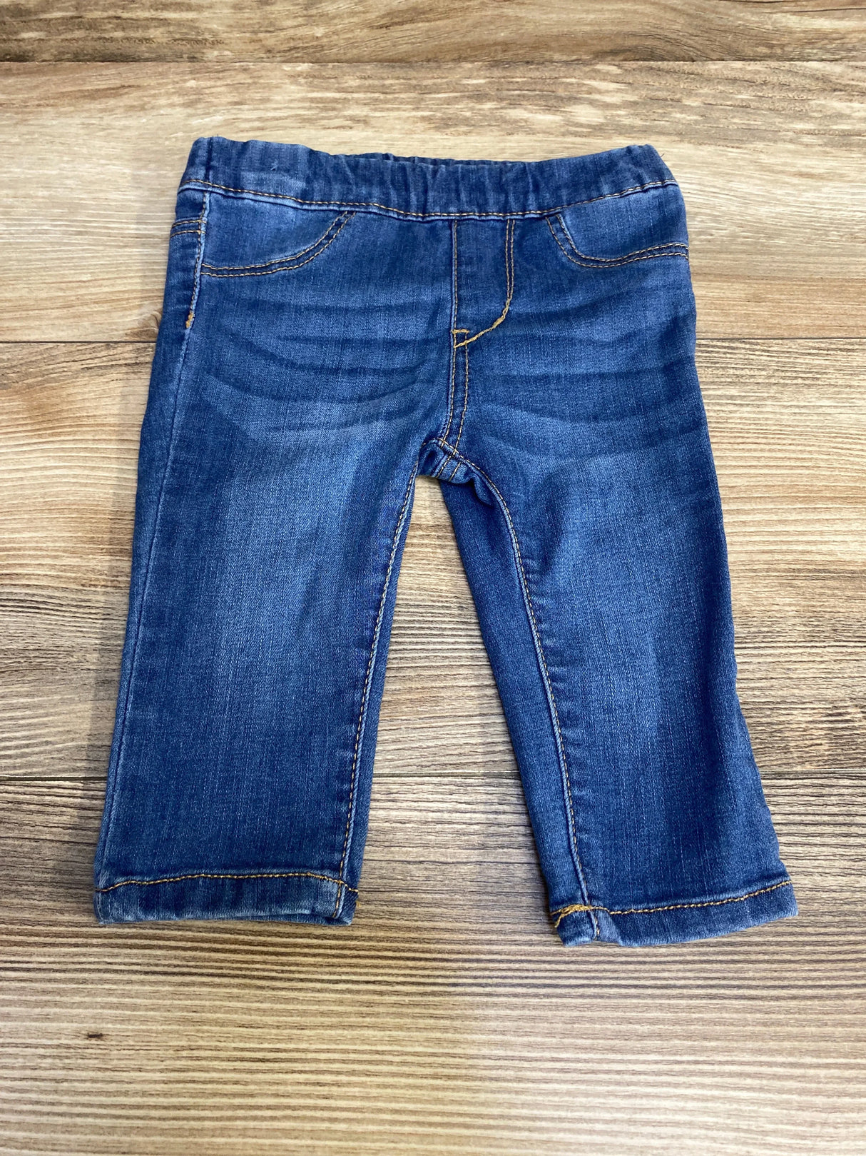 Front view of blue H&M baby jeggings (3-6 months) showing elastic waistband, faux pockets, and stretch denim on wood background