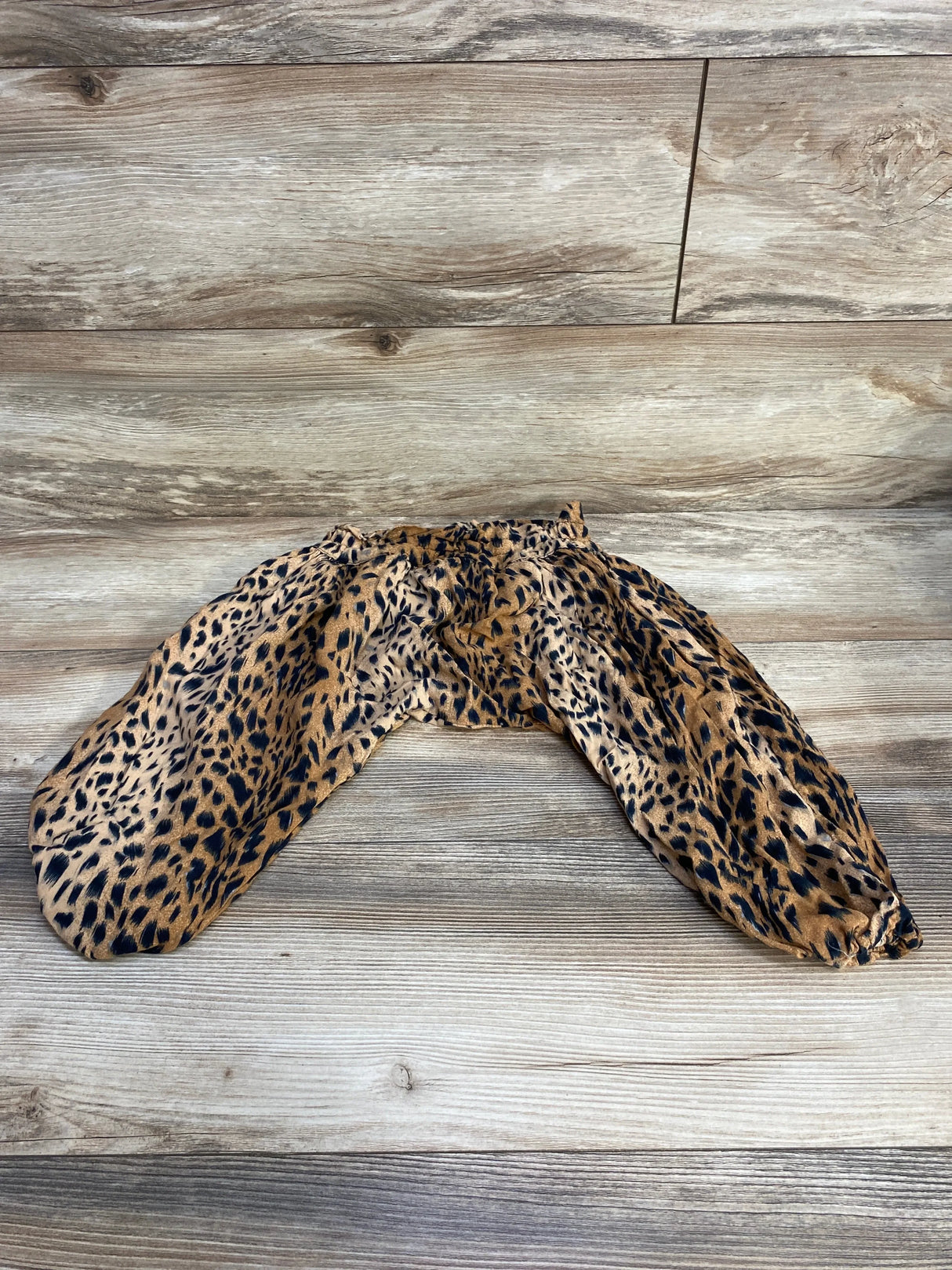 Flat lay of toddler brown animal-print harem pants size 4T showing elastic waistband and gathered ankles on wood background