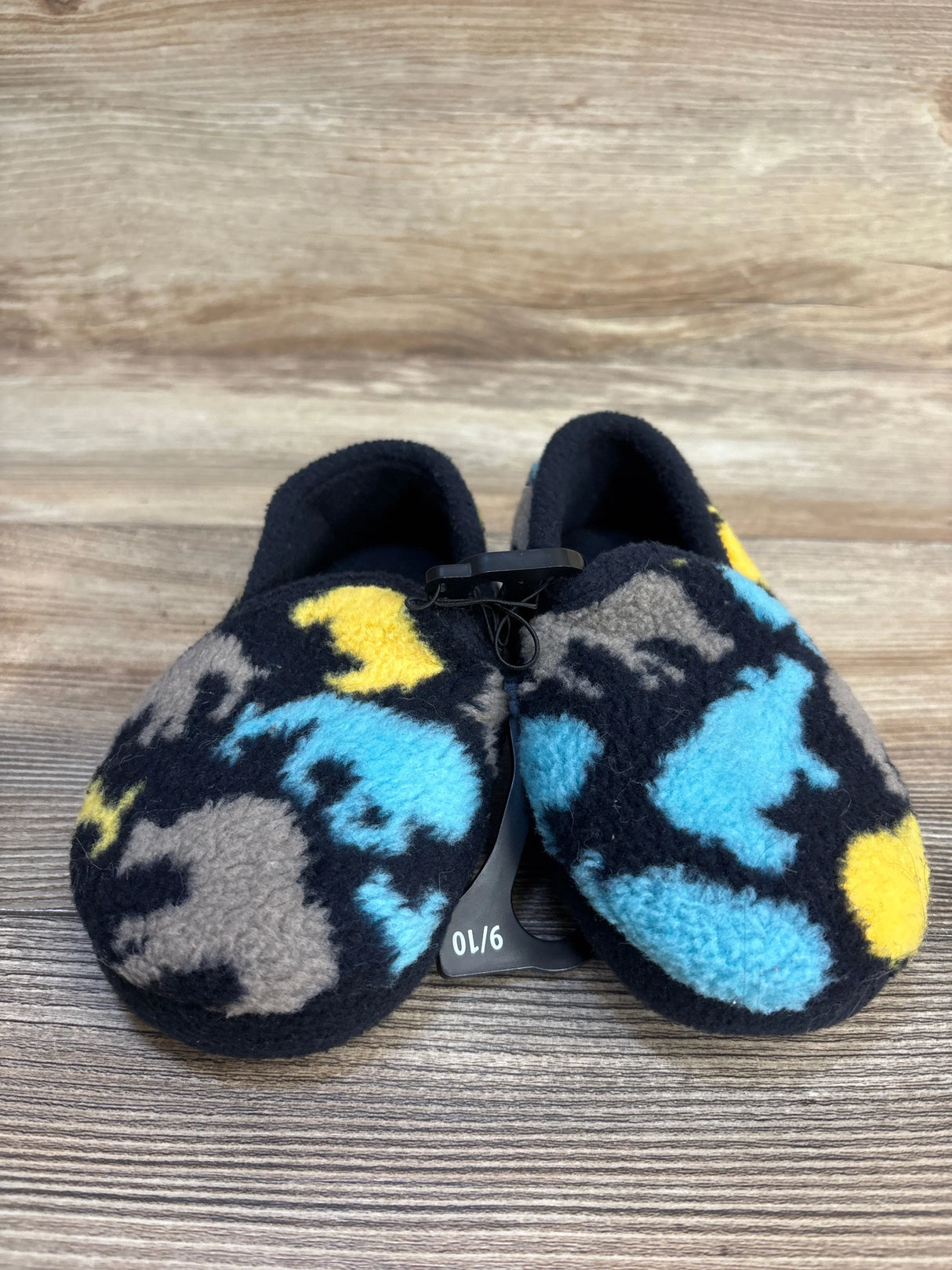 Fleece baby slippers with blue, yellow, and gray animal print on wood background