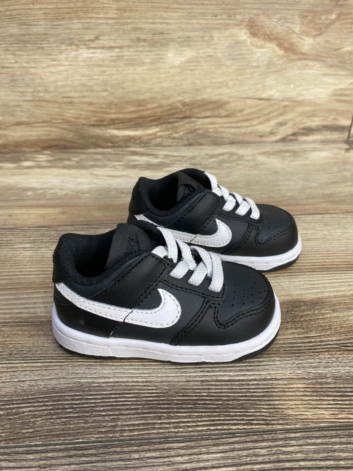 Black and white Nike toddler sneakers on wood background