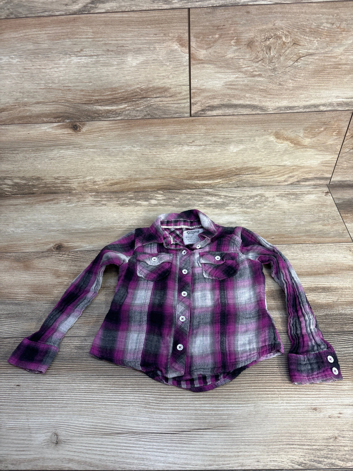 Purple and black plaid long-sleeve button-up shirt on wooden surface