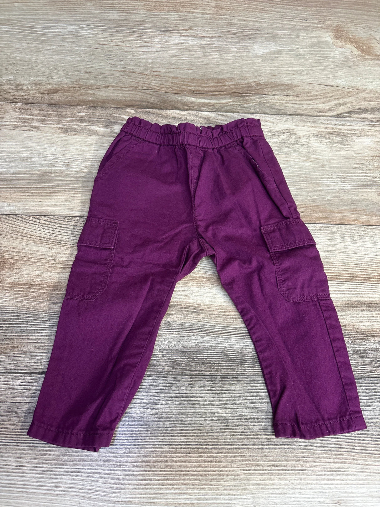 Purple toddler pants with cargo pockets and elastic waistband on wooden floor