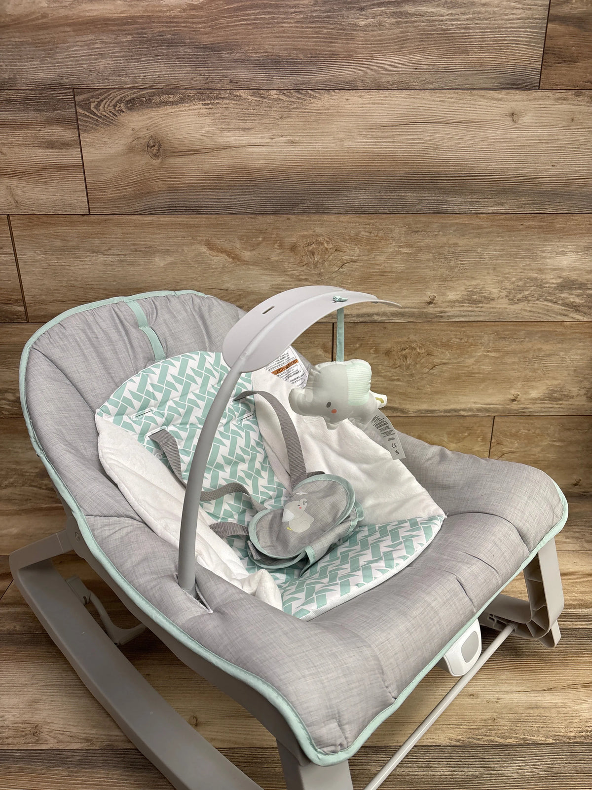 Angled view of Ingenuity Keep Cozy 3-in-1 baby bouncer, rocker and toddler seat with gray upholstery and mint cushion