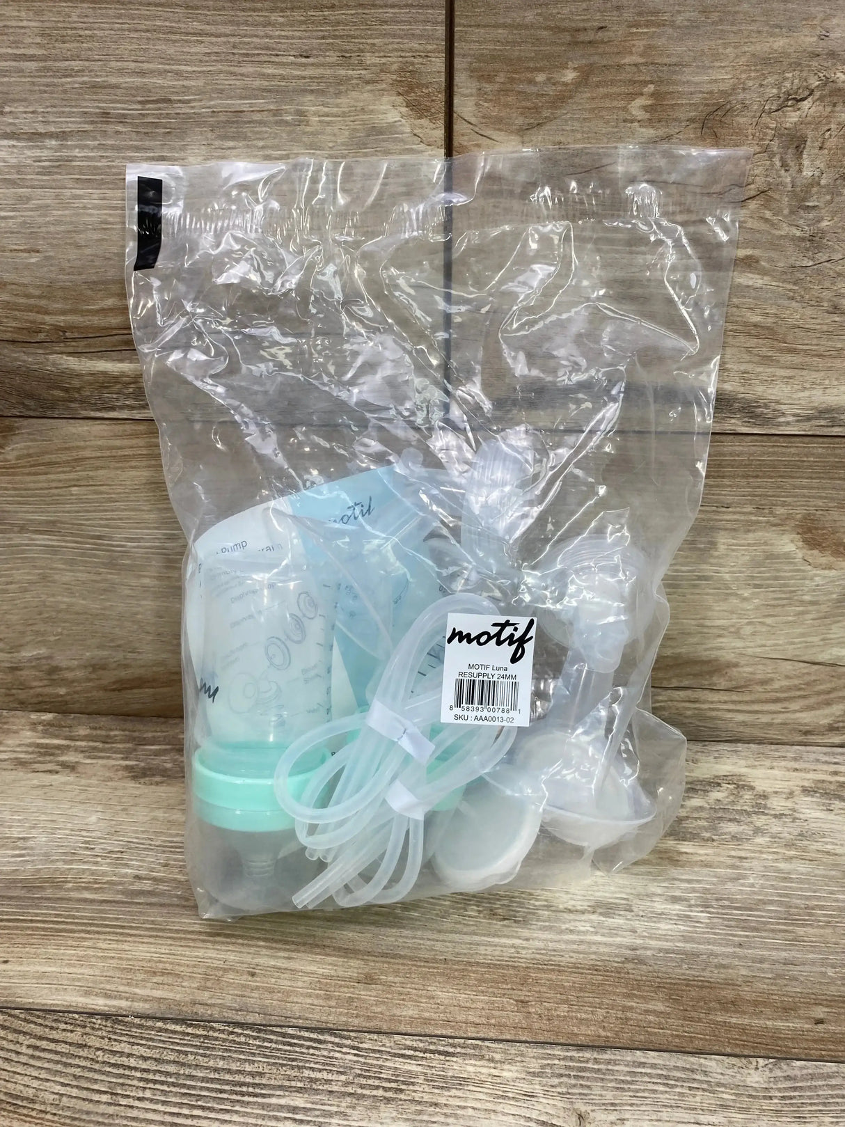 Front view of Motif Luna resupply kit (24mm) showing bottles, tubing, and flanges in a clear bag on wood
