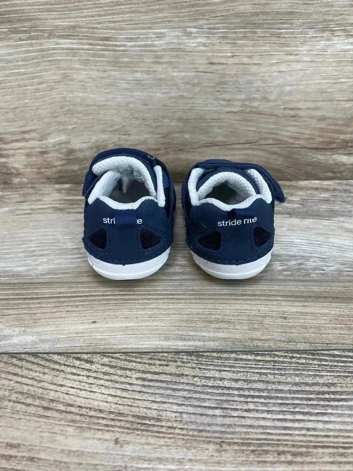 Rear view of Stride Rite Boys Jamie athletic sneakers showing heel branding, cushioned white lining, and Velcro straps on wood background