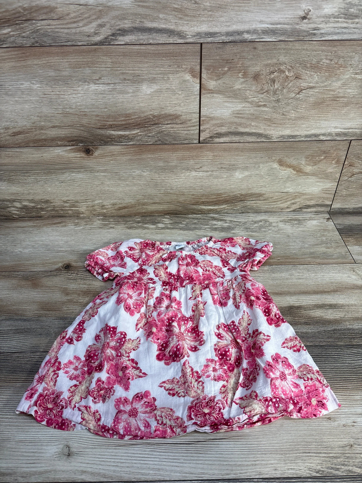 Pink floral baby dress on wood background, cotton short sleeve toddler outfit