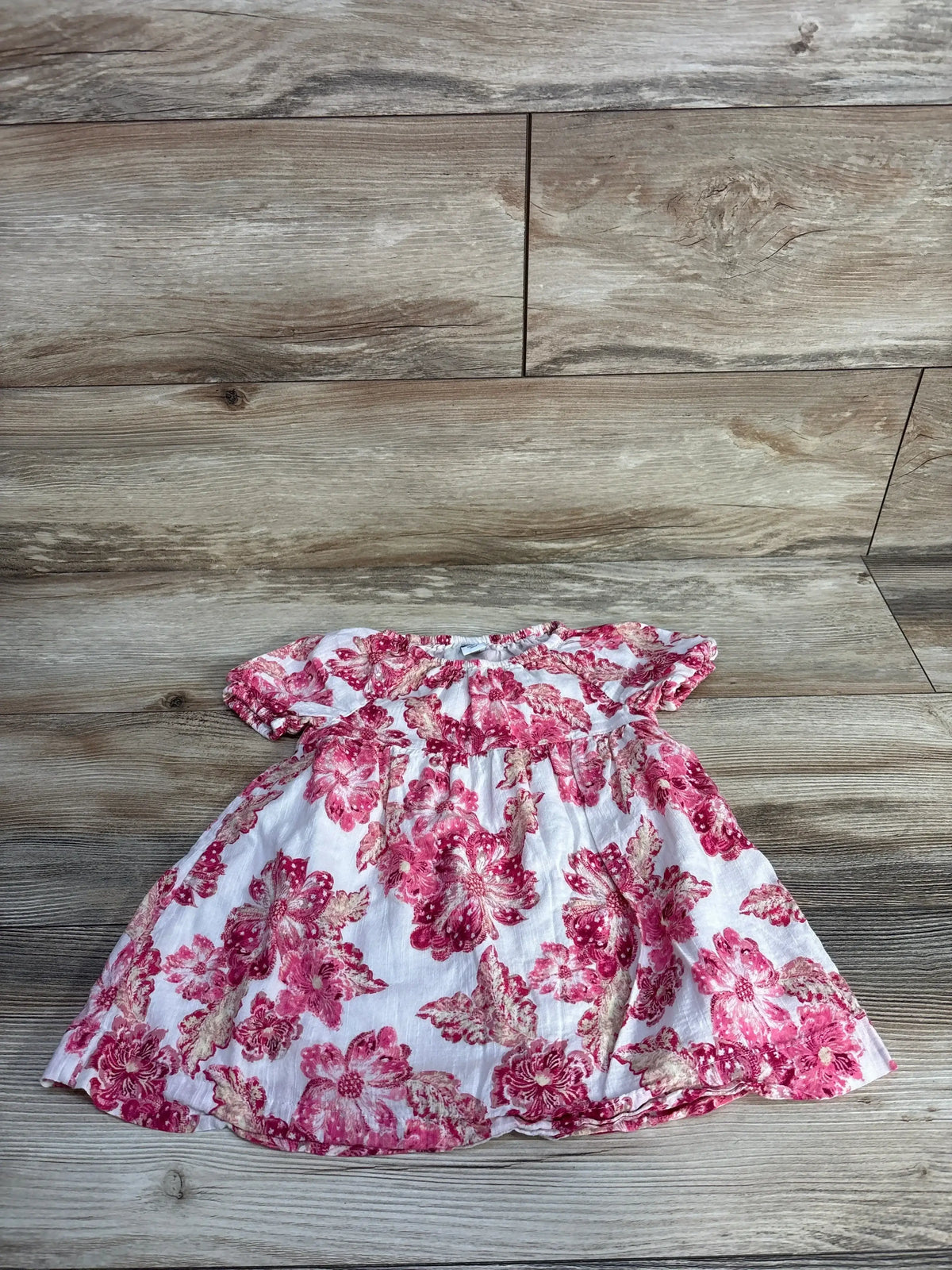Pink floral baby dress on wood background, cotton short sleeve toddler outfit