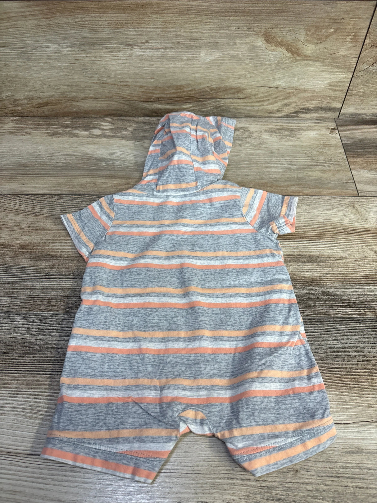 Back view of Carter's hooded shortie romper, grey with orange stripes, short sleeves and snap crotch on wood background