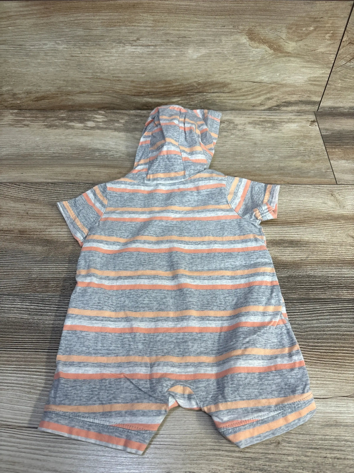 Back view of Carter's hooded shortie romper, grey with orange stripes, short sleeves and snap crotch on wood background