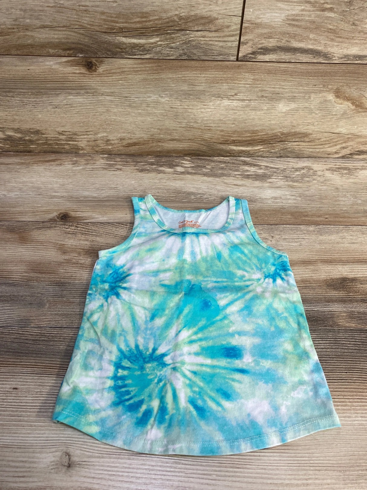 Flat lay of Cat and Jack blue and green tie-dye toddler tank top size 4-5T showing sleeveless A-line shape on wood background