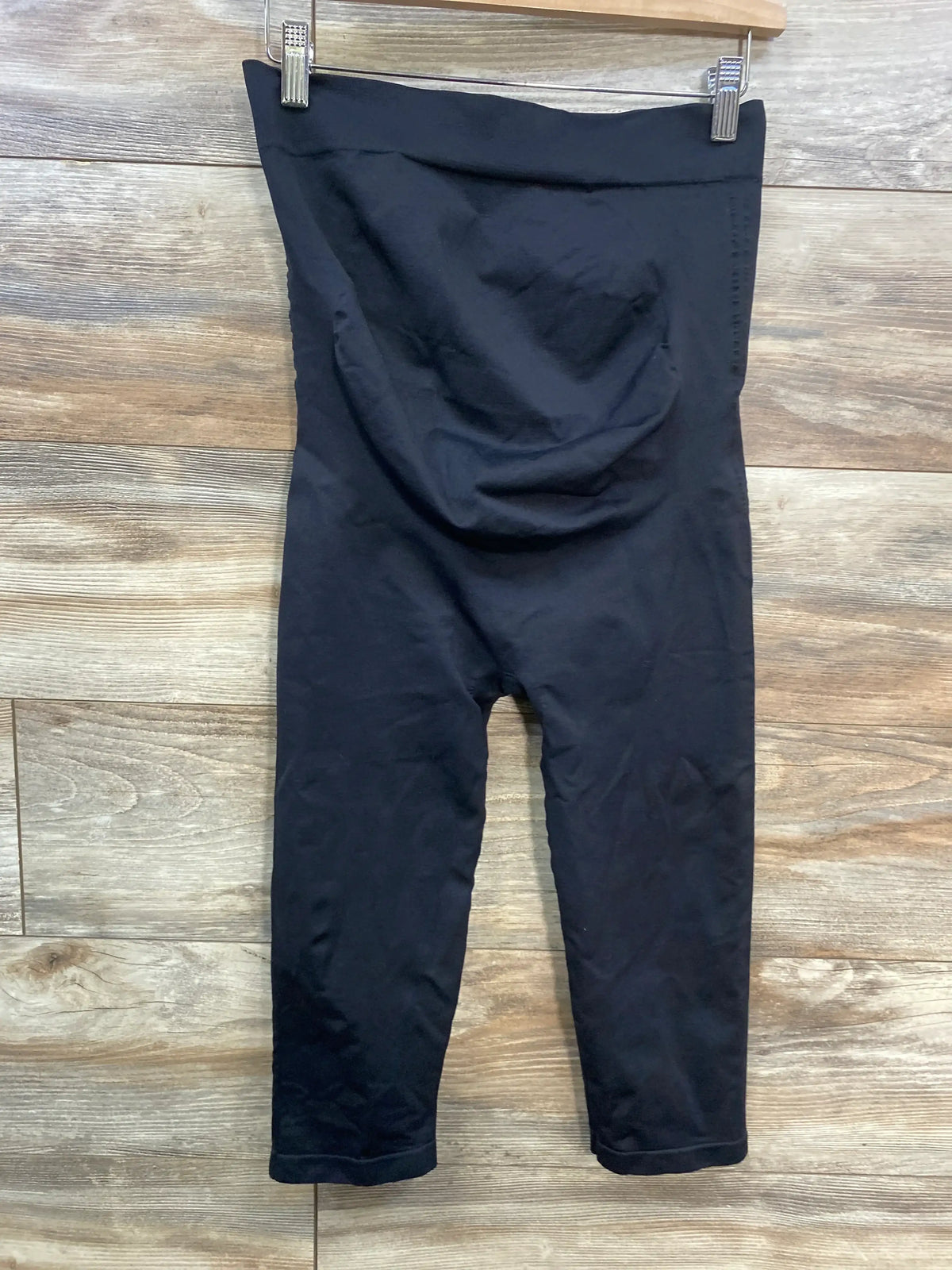 Black maternity leggings with high waistband hanging on wooden background