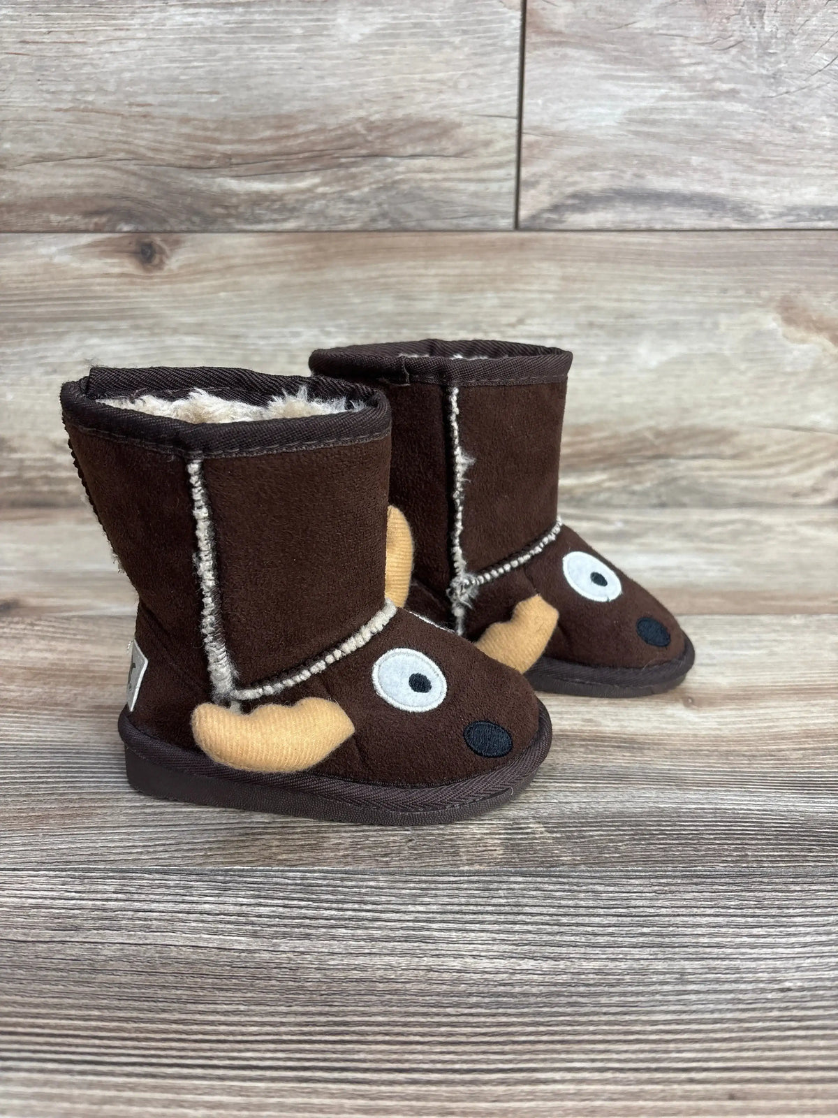 Brown toddler boots with moose face and antlers on wood background