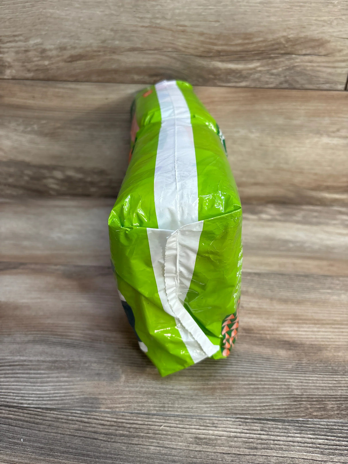 End view of Babyganics Size 2 diaper pack showing green packaging and sealed white stripe on wood tabletop
