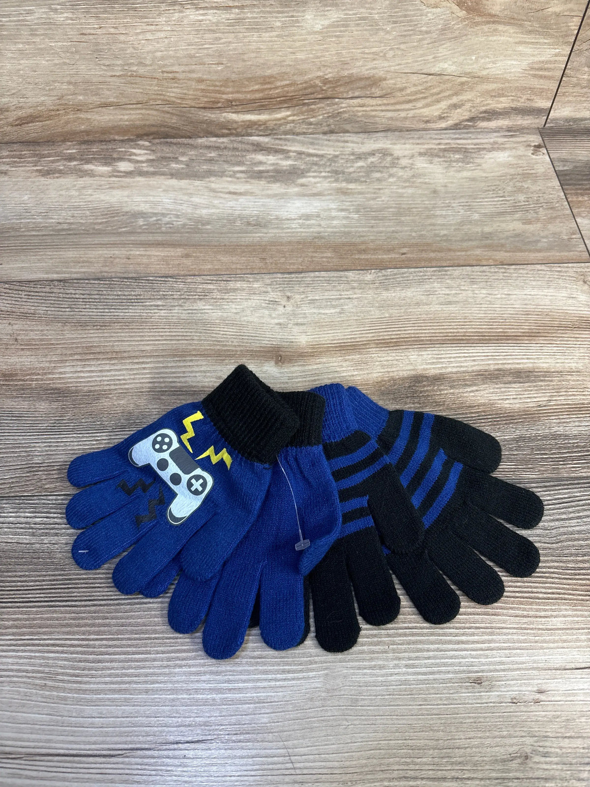 Top view of Toby and Me two-pack gloves showcasing blue and black designs on a wood-look background