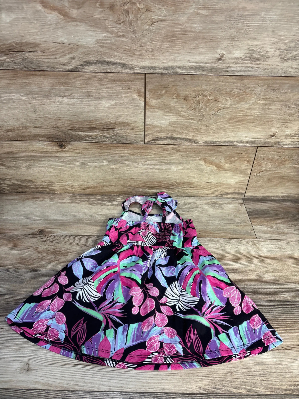 Front view of Children’s Place black floral dress in size 2T, showcasing a floral pattern and flared skirt on wood flooring