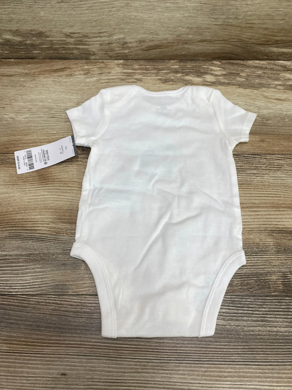 Flat lay of white Carter's short-sleeve baby bodysuit (size 3M) showing back view with attached retail tag on wood background