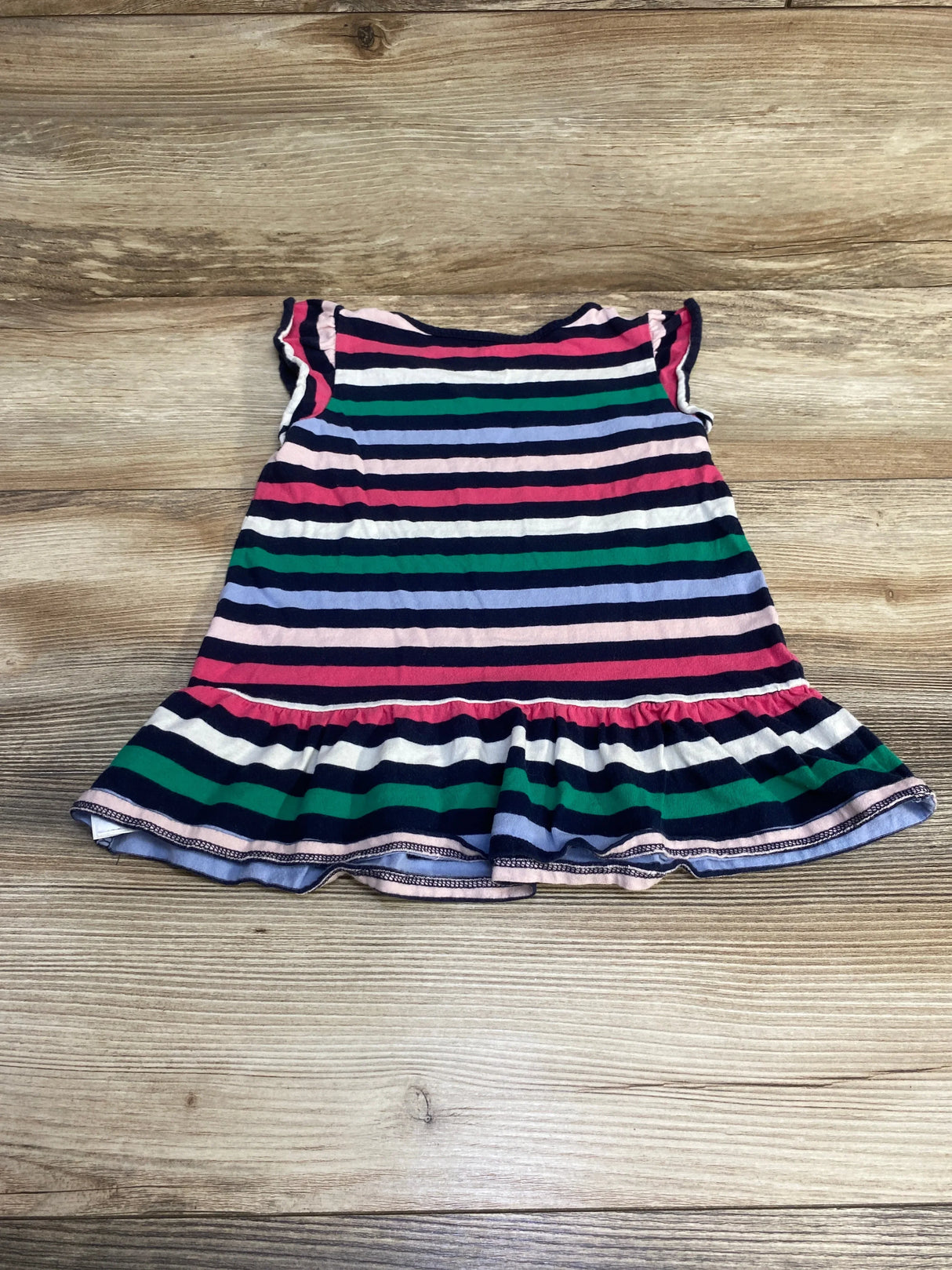 Flat lay of Baby Gap peplum shirt size 4T showing navy multicolor stripes, ruffled hem and cap sleeves on wood background