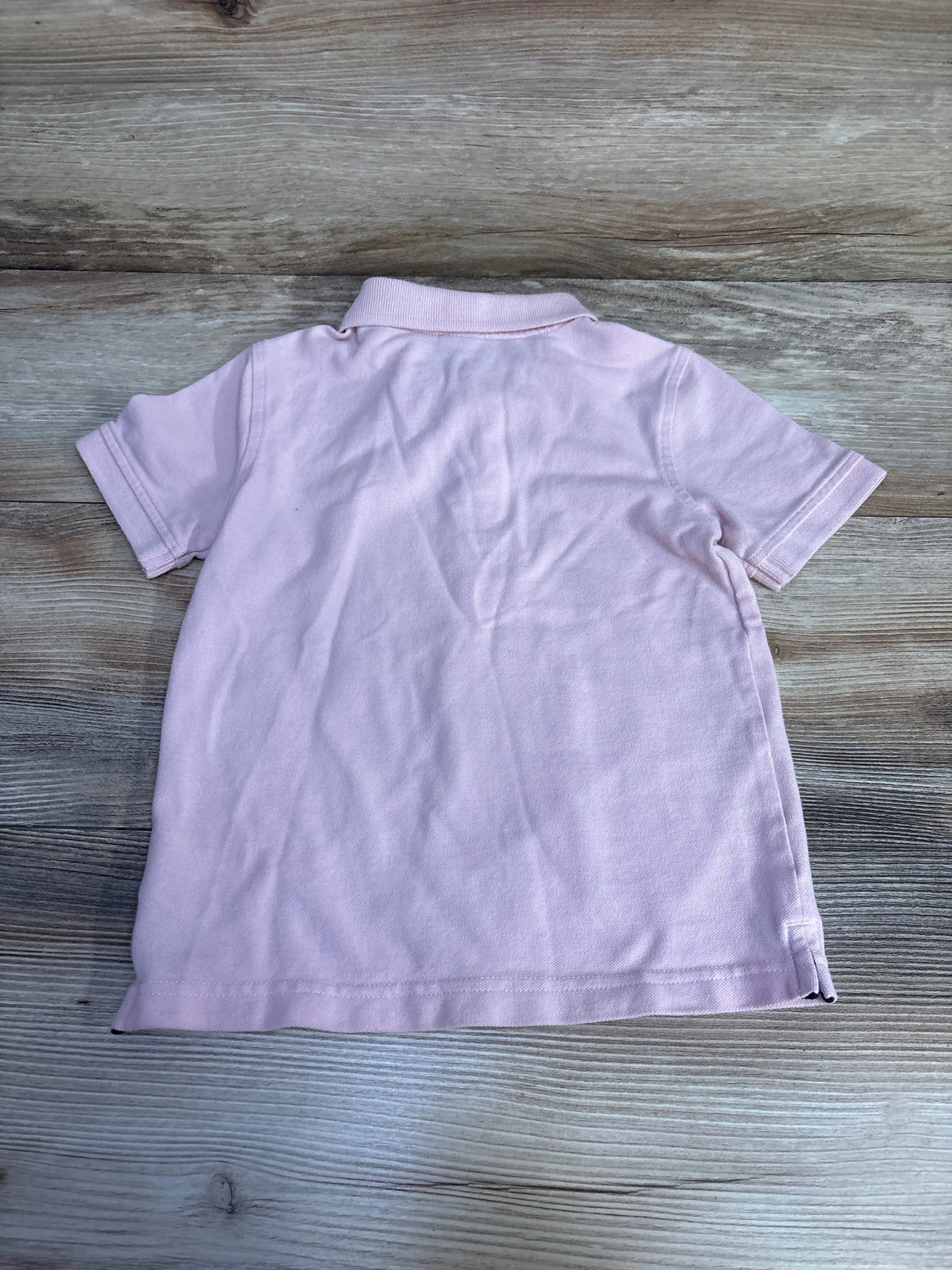 Light pink short sleeve polo shirt on wood background