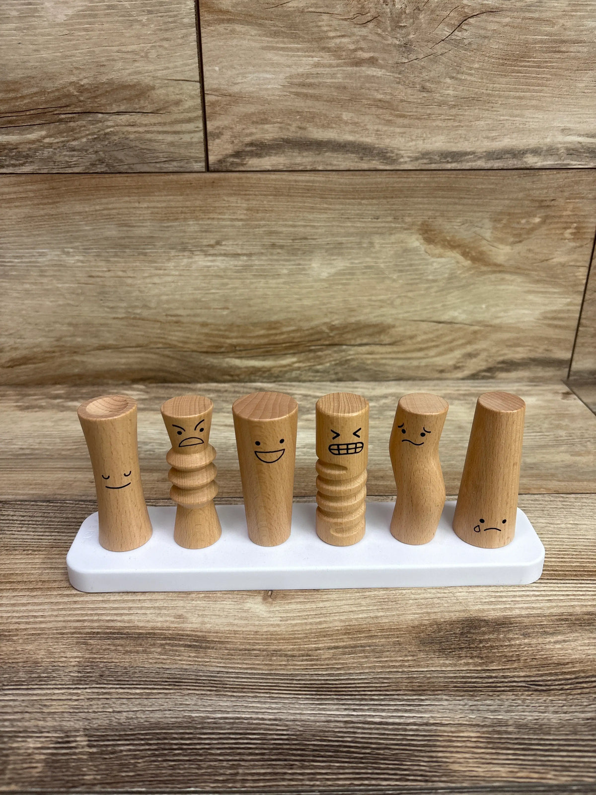 Front view of Lovevery Wooden Emotion Dolls showing six wooden figures with different facial expressions on a white base