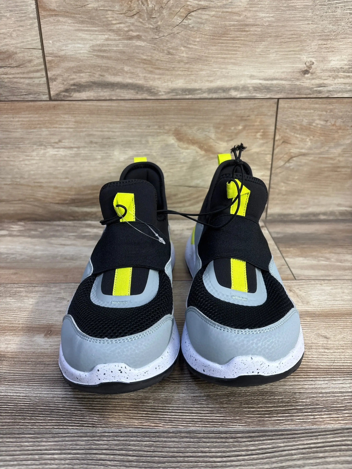 Front view of All In Motion Fern slip-on sneakers showcasing black and gray uppers with lime green detailing on a wood floor