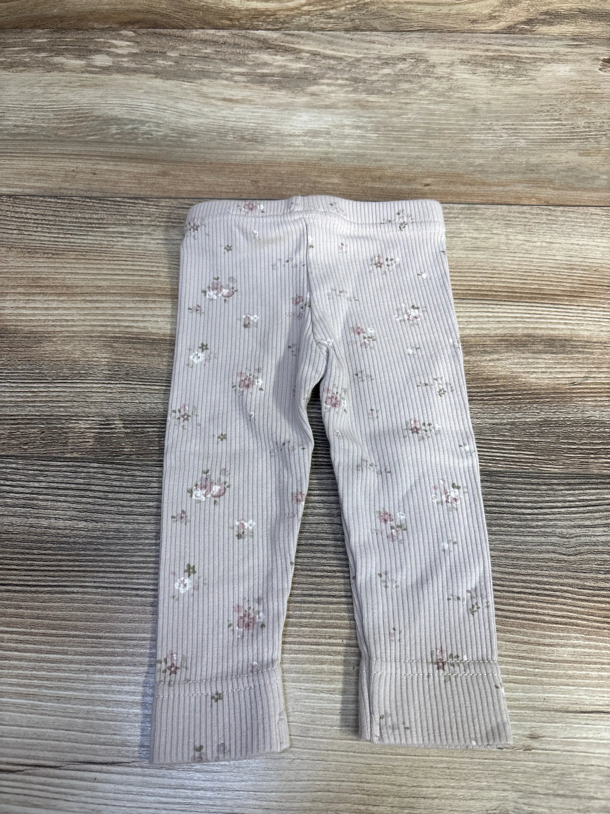 Front view of Jamie Kay lilac newborn leggings showcasing ribbed knit, floral pattern, and elastic waistband on wooden background