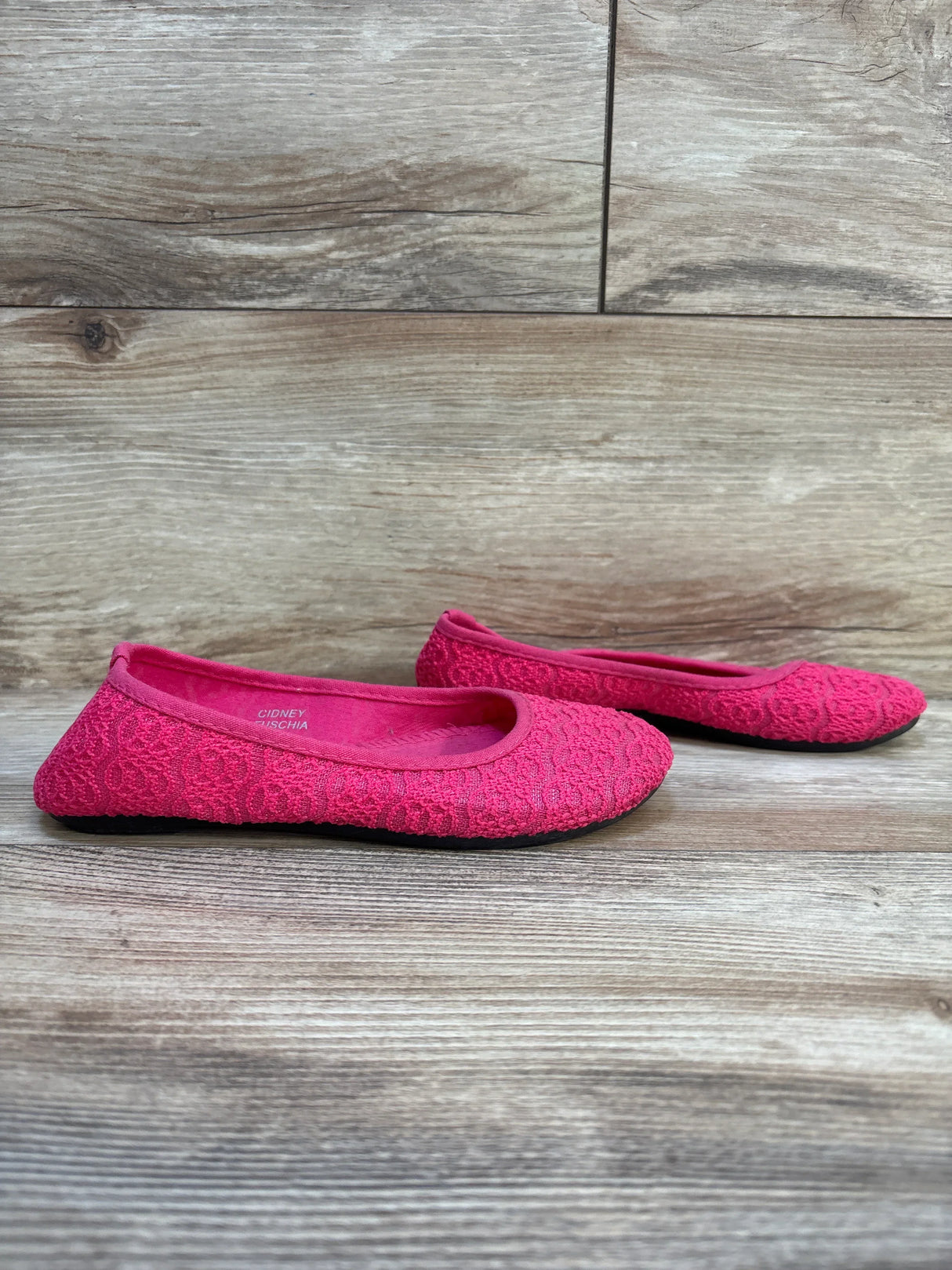 Side view of Sugar Kids lace flats in pink, size 2Y, showcasing lace texture and black rubber soles on wood floor