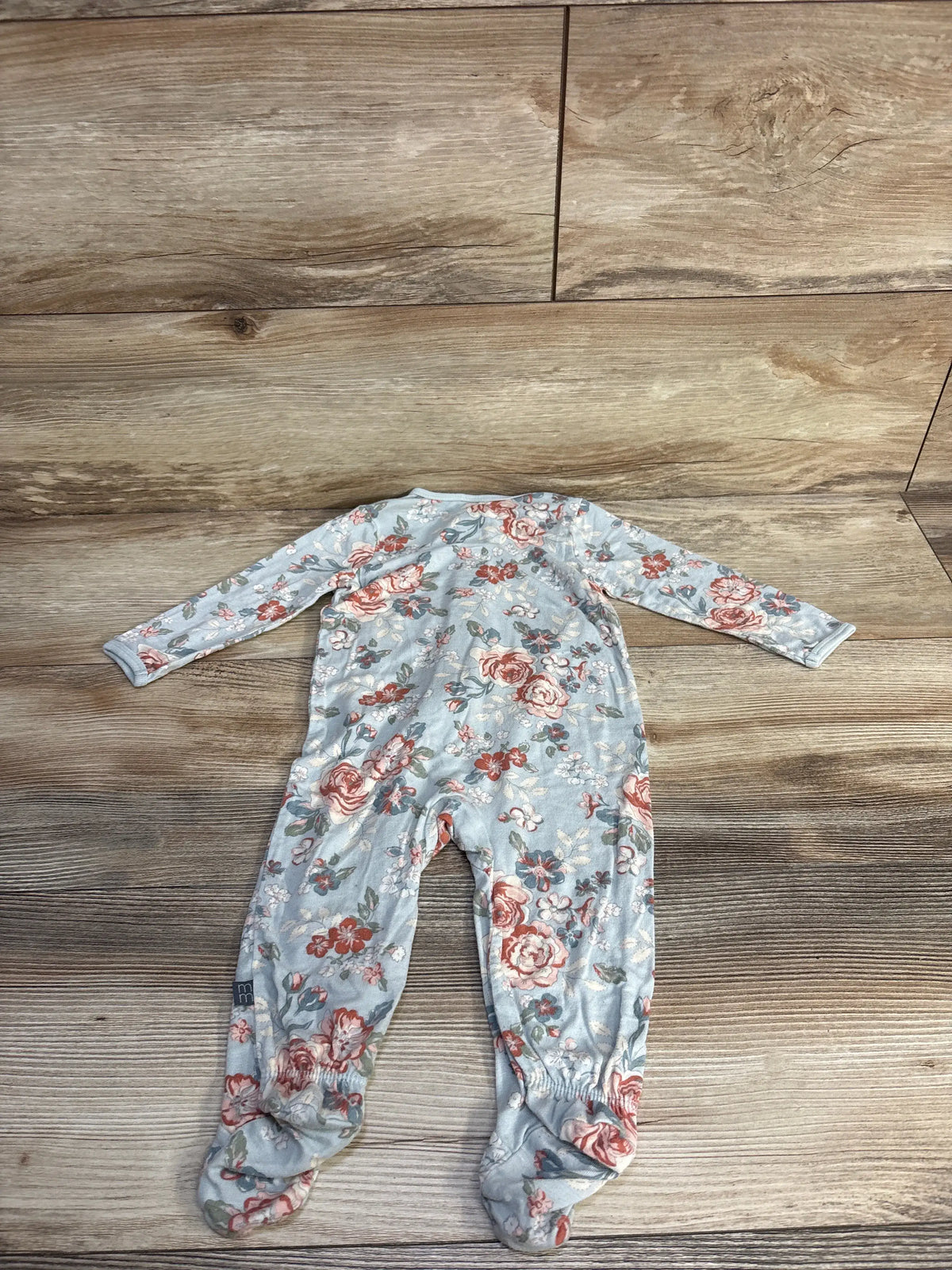 Front view of Modern Moments viscose sleeper with blue floral fabric, long sleeves, and footed legs on wood-look background