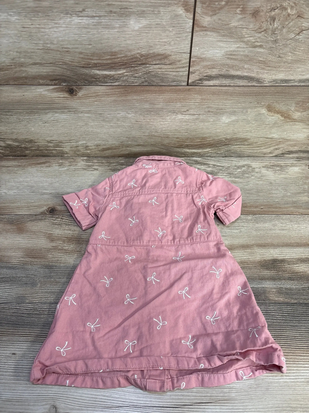 Back view of pink Nanette button-up shirt dress size 18m showing white embroidered bows and rolled sleeves on wood background