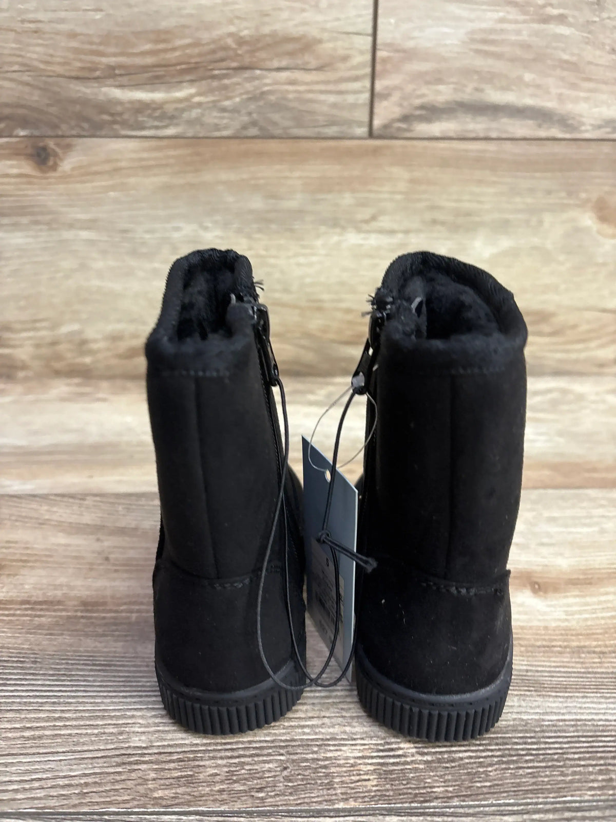 Black suede toddler boots with faux fur lining, rear view on wooden floor