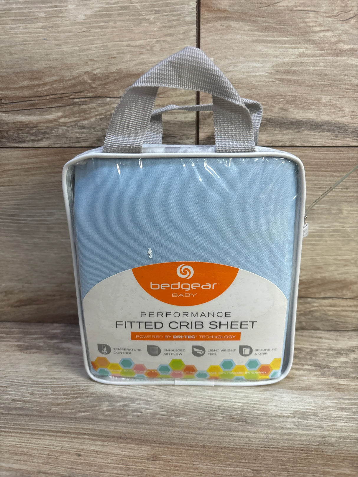 Front of packaged Bedgear Baby Dri-Tec fitted crib sheet in light blue with label and handle on wood background