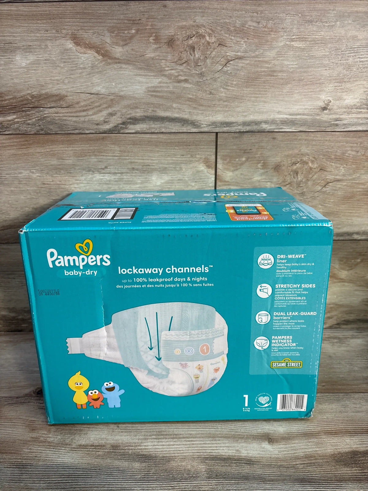 Front view of NEW Pampers Baby Dry Diapers 120ct Size 1 box showcasing lockaway channels on a wood background