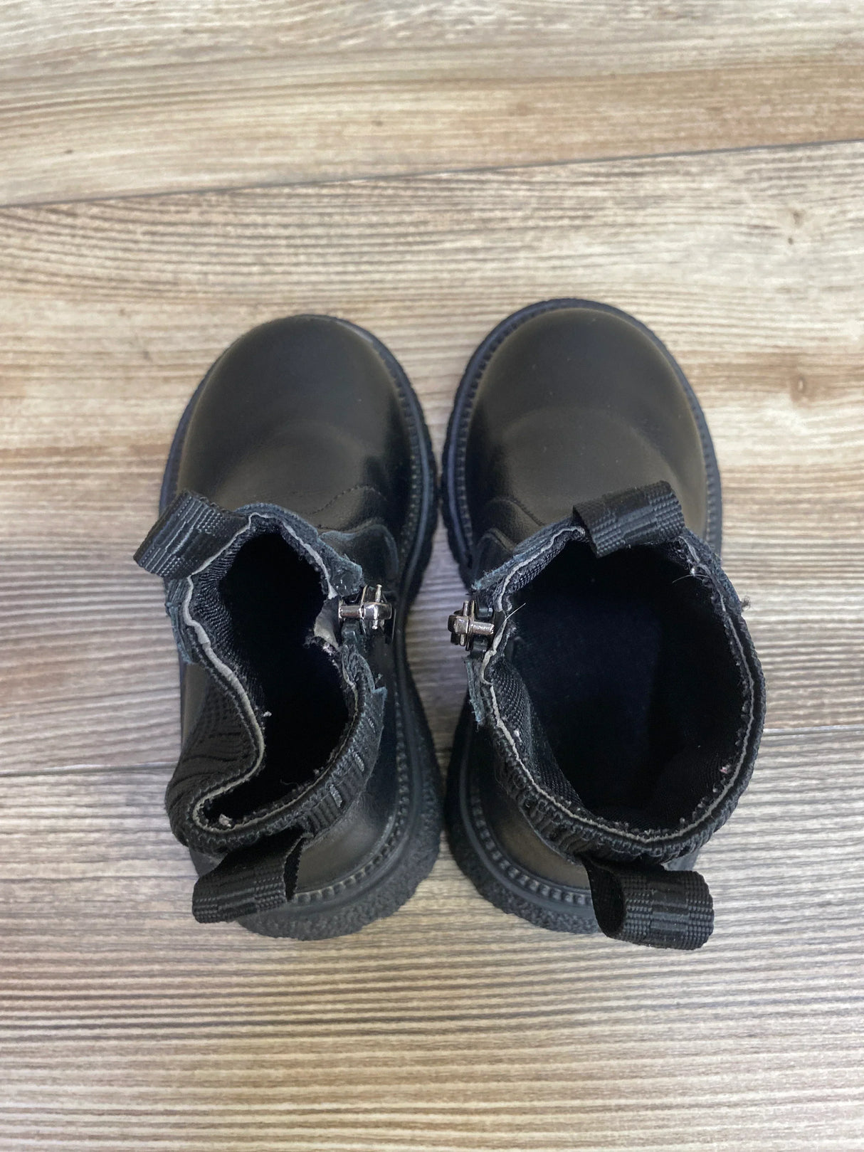 Black toddler combat boots with loops, displayed on wood floor, kids footwear resale