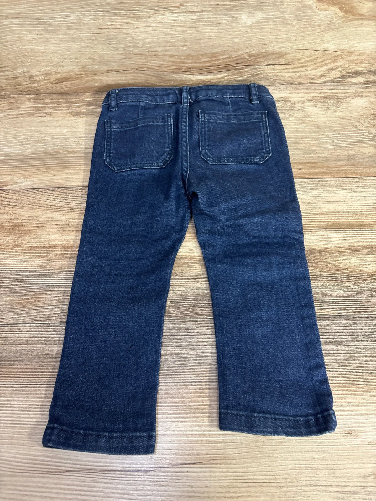 Back view of Jacadi Paris navy toddler comfort jeans showing back patch pockets and straight legs on wood surface