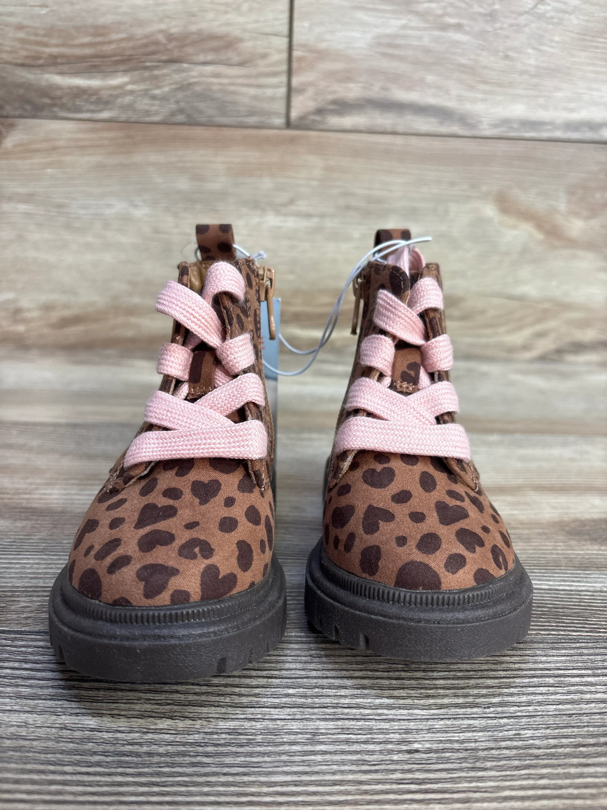 Kids' leopard print boots with pink laces on wood background